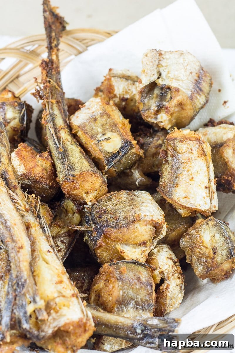 Sweet Heat Fish 4 Crispy, golden-brown fried fish pieces resting on paper towels to drain excess oil, prepared for the Nigerian Peppered Fish sauce.