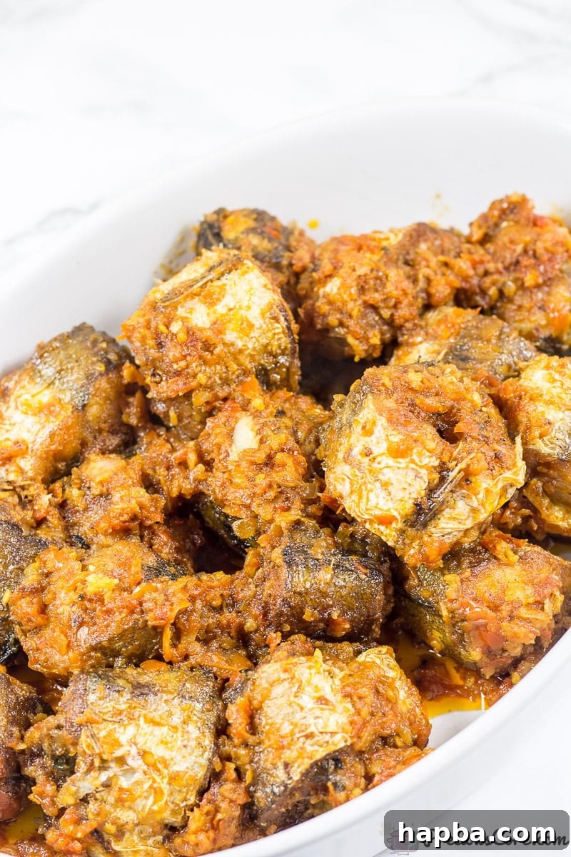 Sweet Heat Fish 5 Cooked Nigerian Peppered Fish, with golden fried fish immersed in a vibrant, rich, and spicy tomato-based sauce.