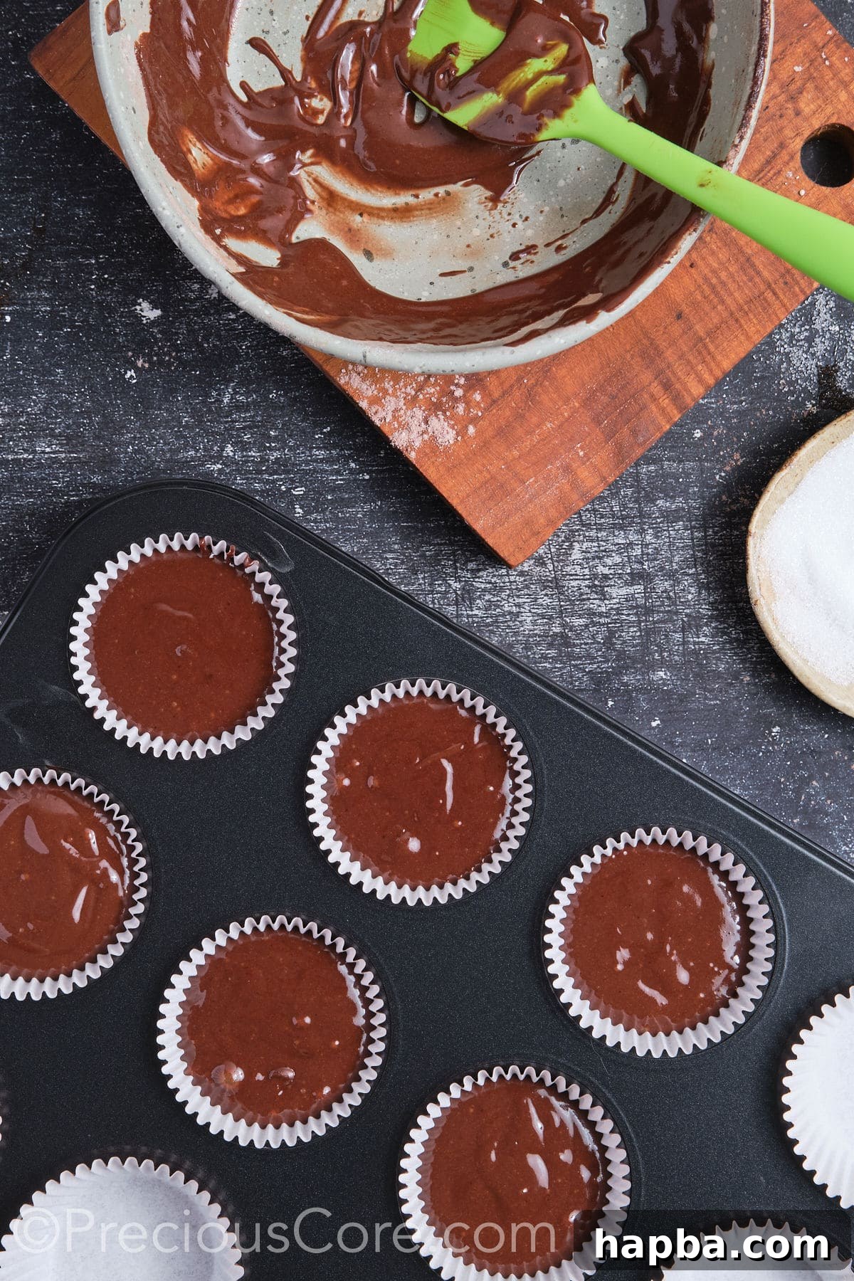 Chocolate cupcake batter in a muffin pan, perfectly portioned and ready for baking.
