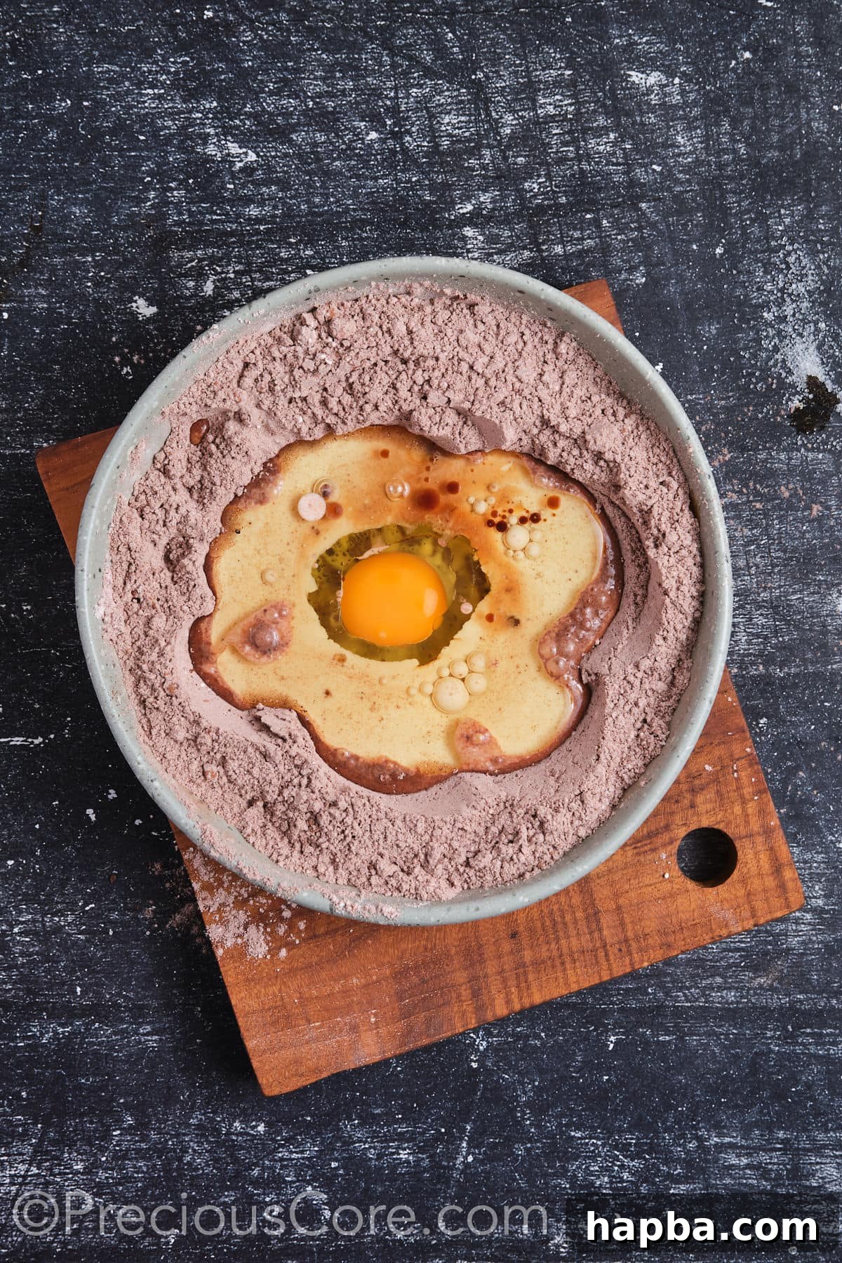 Adding wet ingredients, including eggs, oil, and vanilla, to the dry ingredients in a bowl.