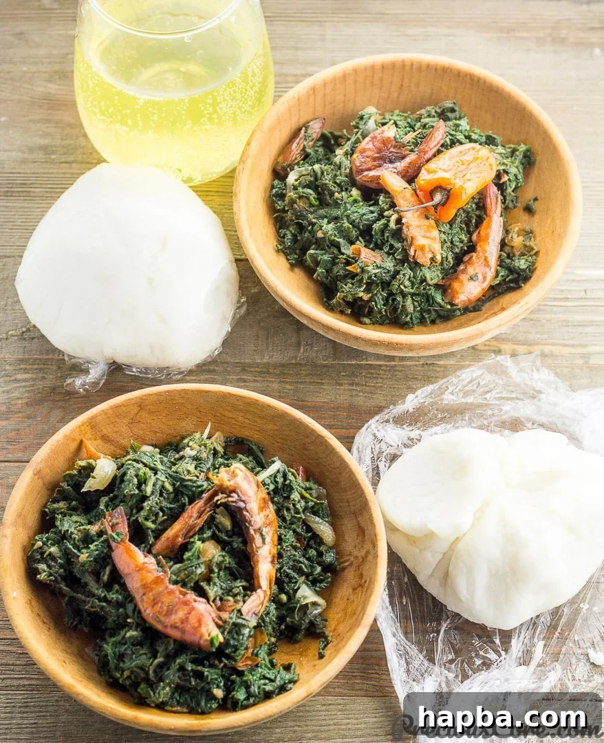 A hearty meal featuring Corn Fufu served alongside a rich pumpkin leaf stew, a classic pairing.