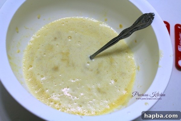 A bowl containing mashed bananas, eggs, and milk being mixed together
