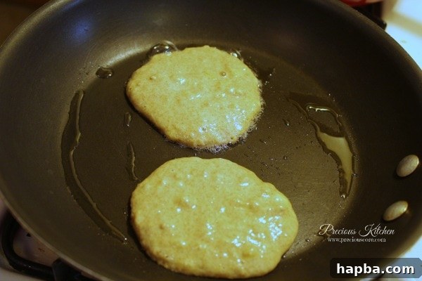 Pancake batter cooking on a hot non-stick frying pan, forming small circles