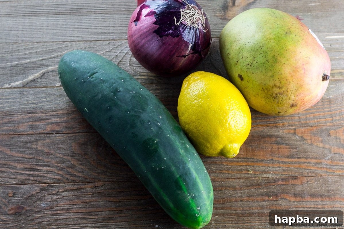 Sunshine Mango Cucumber Medley 4 Arrangement of fresh ingredients including cucumber, mango, red onion, lemon, honey, and olive oil for the salad.