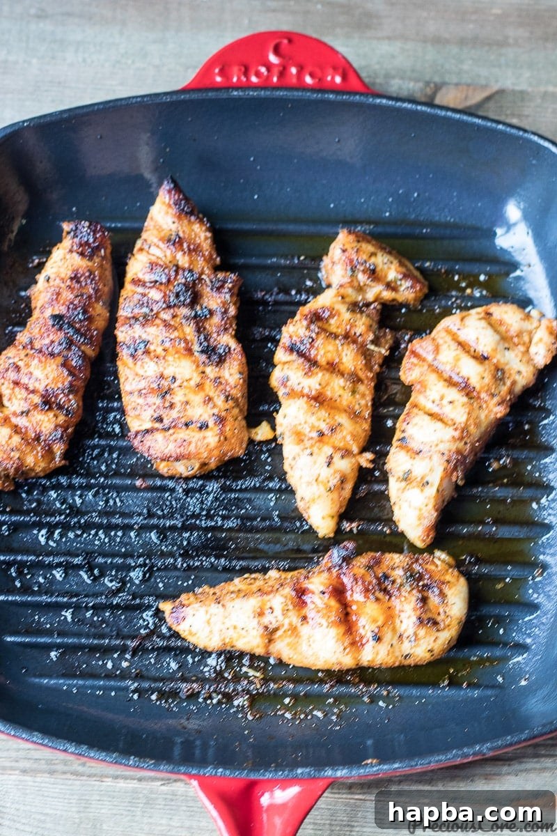 Succulent Grilled Chicken Strips 4 Grilled chicken tenders cooking in a cast iron grill pan on the stovetop