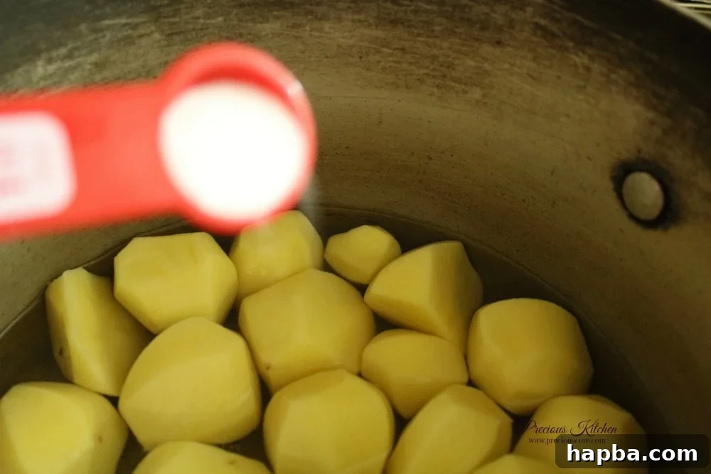 Peeled Irish potatoes boiling with a pinch of salt, ready for mashing in Cameroonian Mashed Potatoes and Beans.