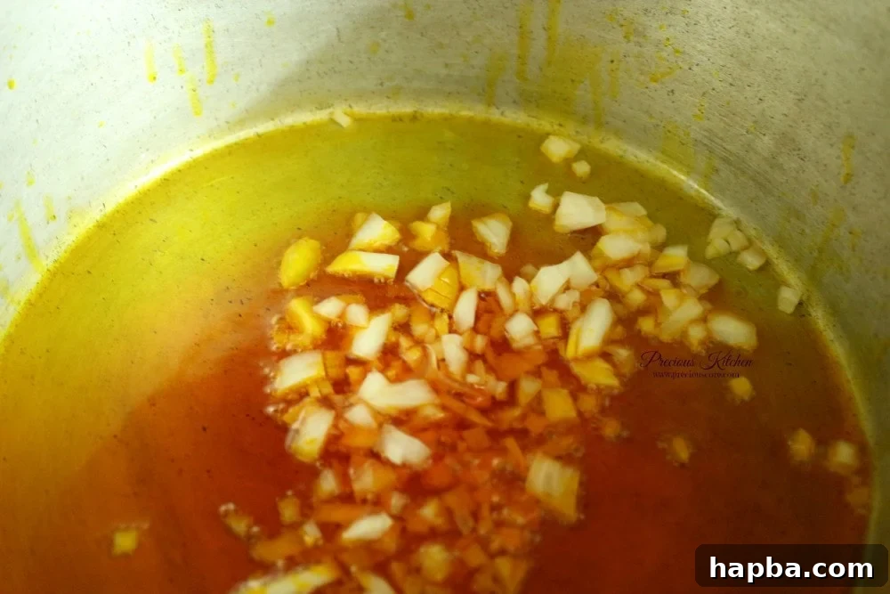 Finely chopped onions sizzling in heated red palm oil, creating an aromatic foundation for Cameroonian Mashed Potatoes and Beans.