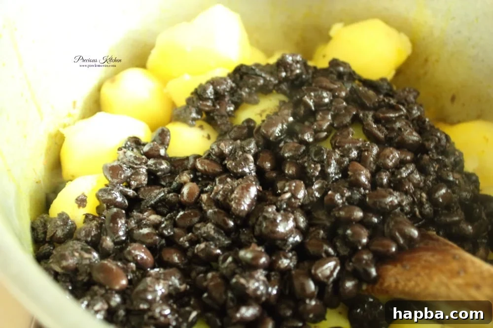 Boiled potatoes and beans freshly added to the aromatic palm oil base, ready for mashing into Tukuni.