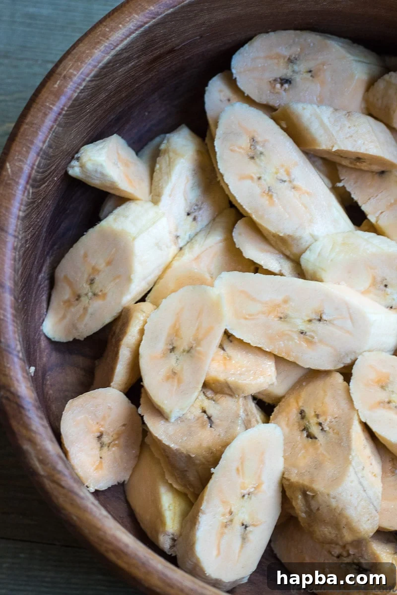 Slices of sweet plantains in a wooden bowl, uniformly cut.