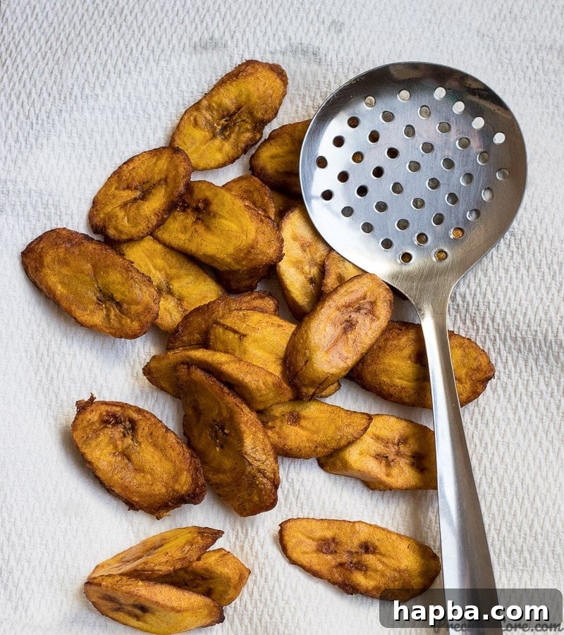 Golden brown sweet fried plantains on paper towels, draining excess oil.