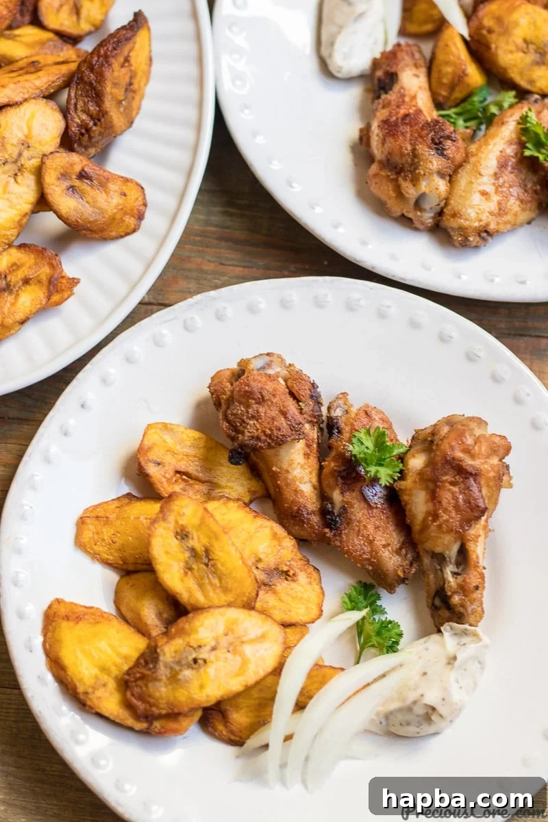 Sweet fried plantains on a white plate with oven grilled chicken wings, a complete meal.