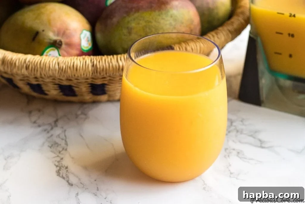 A close-up shot of homemade mango juice in a clear glass, showing its smooth texture and rich color.