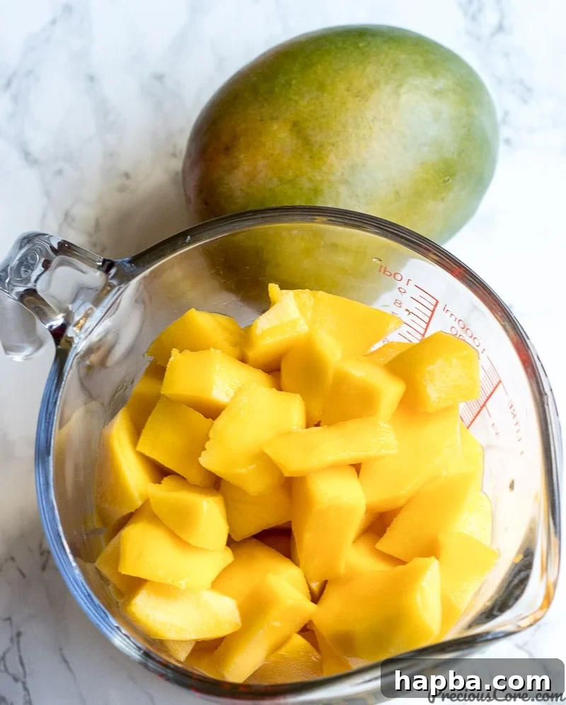A small bowl brimming with freshly peeled and uniformly diced mango pieces, ready for the blender.