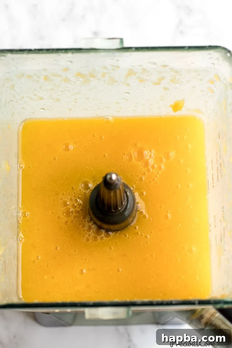 The blender jug filled with a vibrant, freshly pureed mango juice, demonstrating its smooth texture.