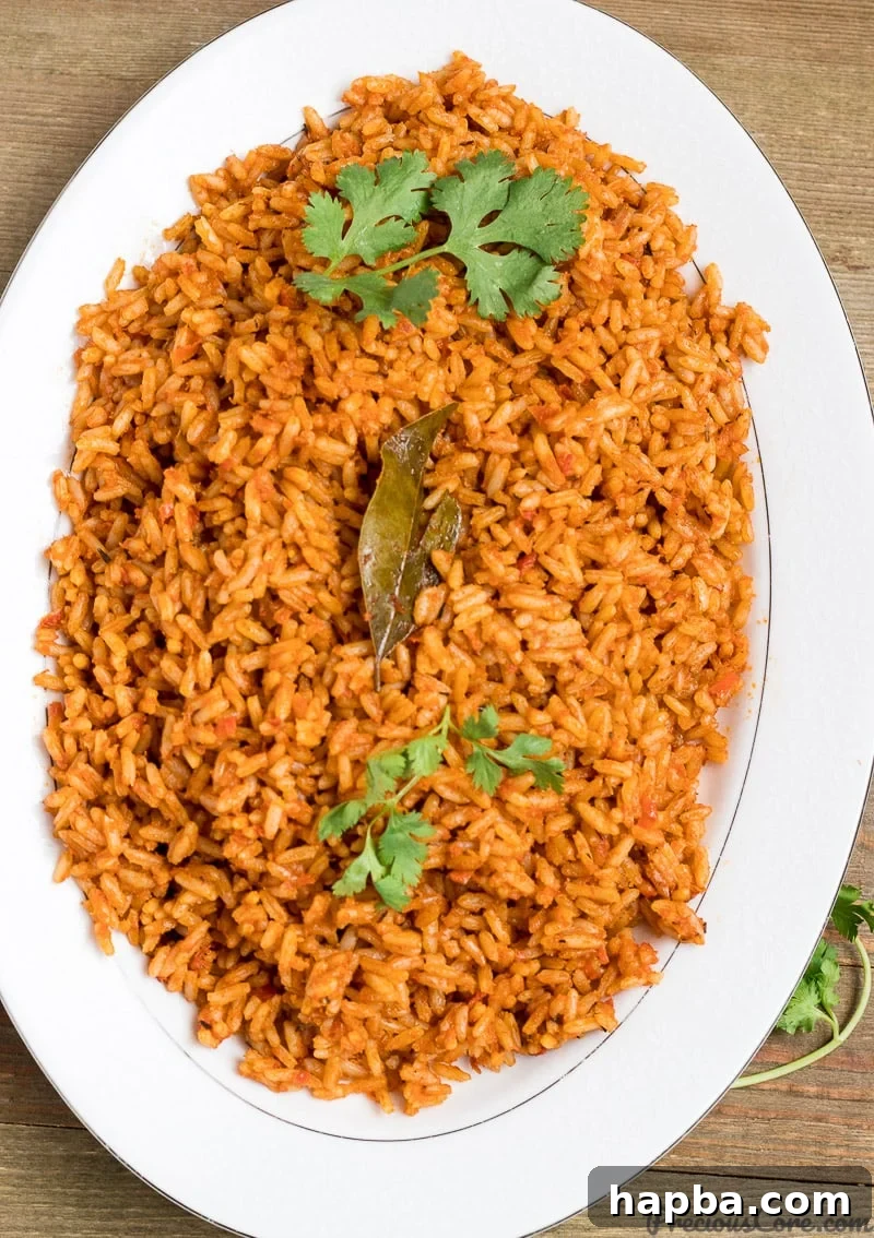Authentic Nigerian Jollof Rice, a vibrant orange-red rice dish served with fried chicken.