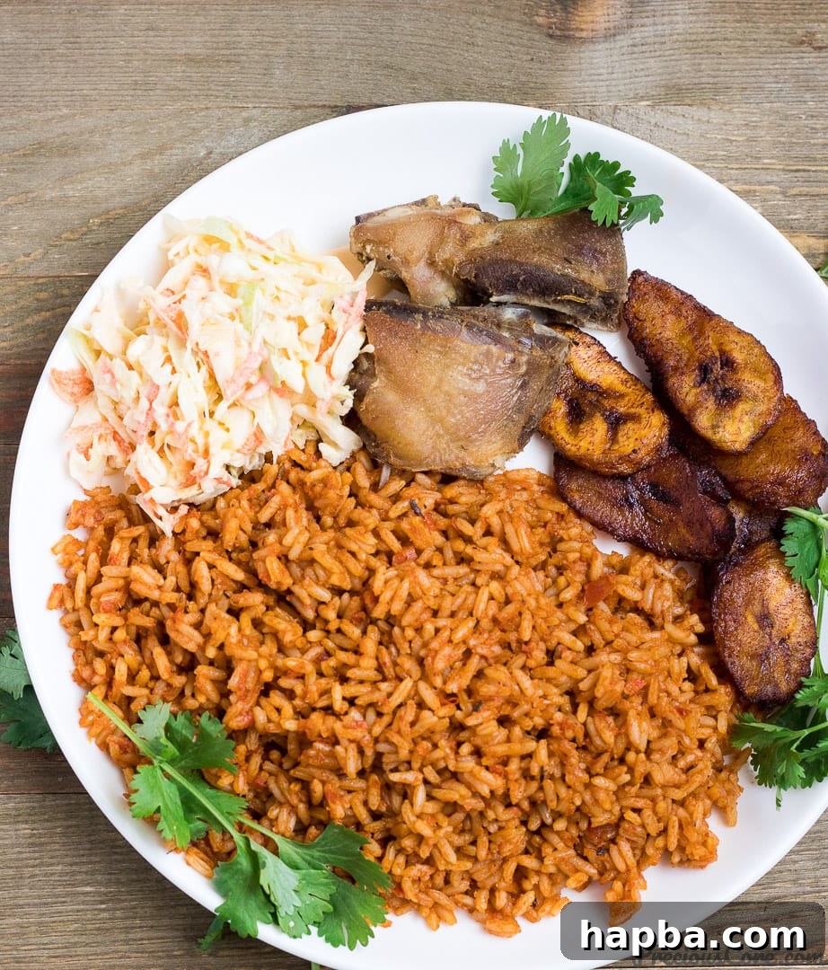 Nigerian Jollof Rice, a rich, red rice dish with a side of crispy fried chicken, showcasing the recipe.