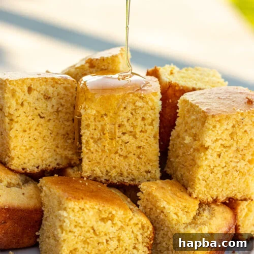 Square slices of cornbread without buttermilk with honey drizzling on top.