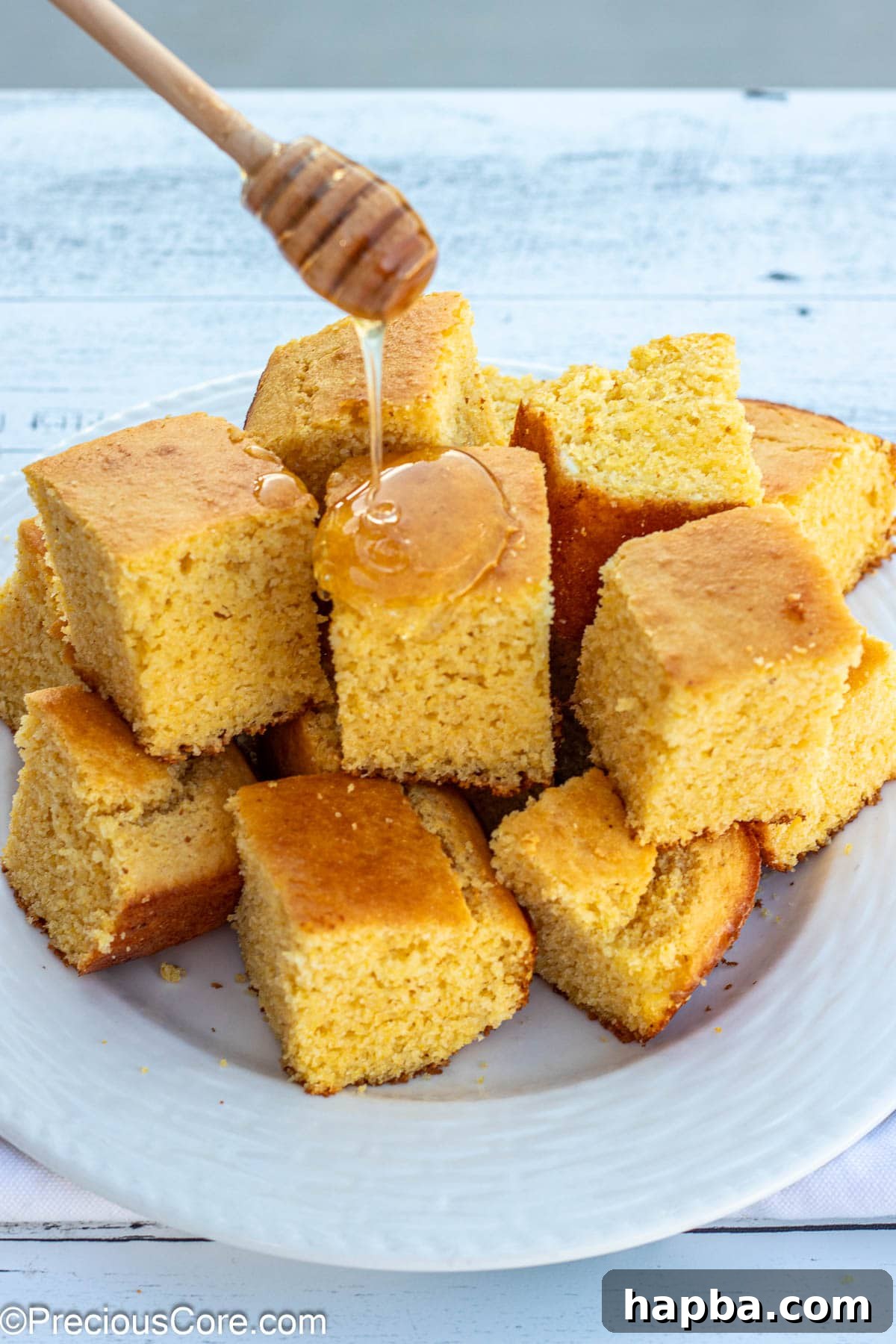 Moist Cornbread Without Buttermilk 4 A honey wand elegantly drizzling golden honey over warm slices of homemade cornbread, a perfect sweet addition.