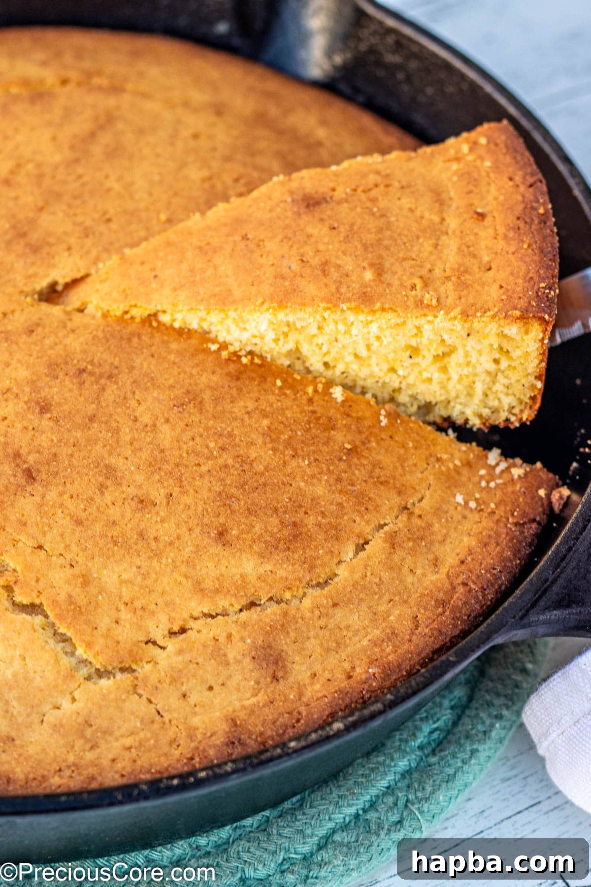 Moist Cornbread Without Buttermilk 10 A delectable slice of warm cornbread being carefully lifted from a cast iron skillet, ready to be enjoyed.