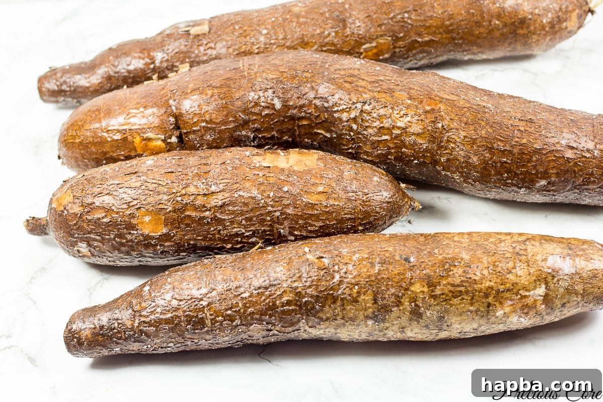 Four fresh cassava roots on a kitchen counter, ready for preparation.