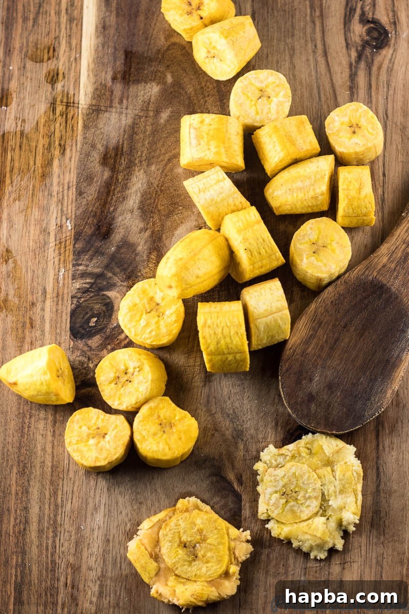 Crispy Tostones: Mastering the Twice-Fried Plantain 6 Wooden spoon with flattened plantains.