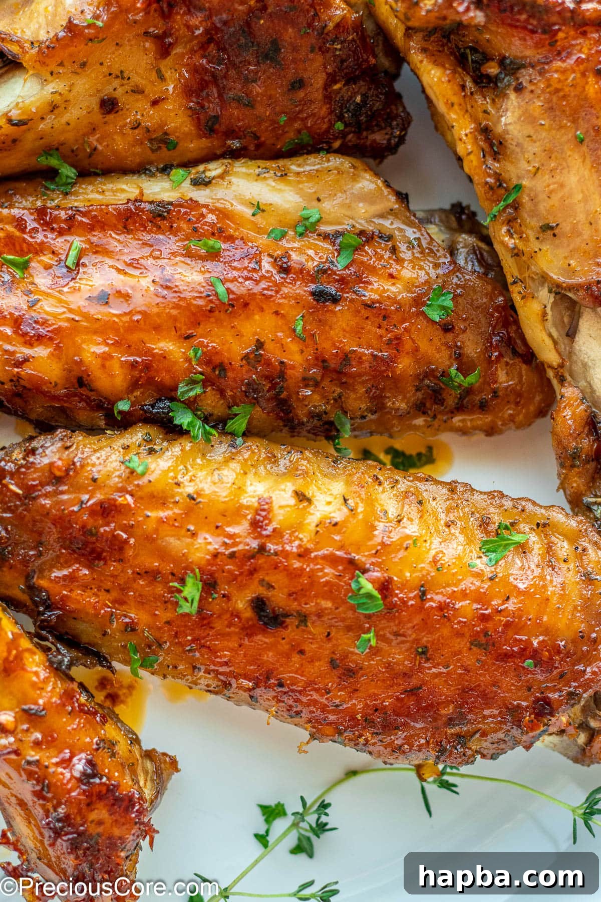 Golden brown oven baked turkey wings in a white serving bowl, garnished with fresh herbs, ready to be enjoyed.