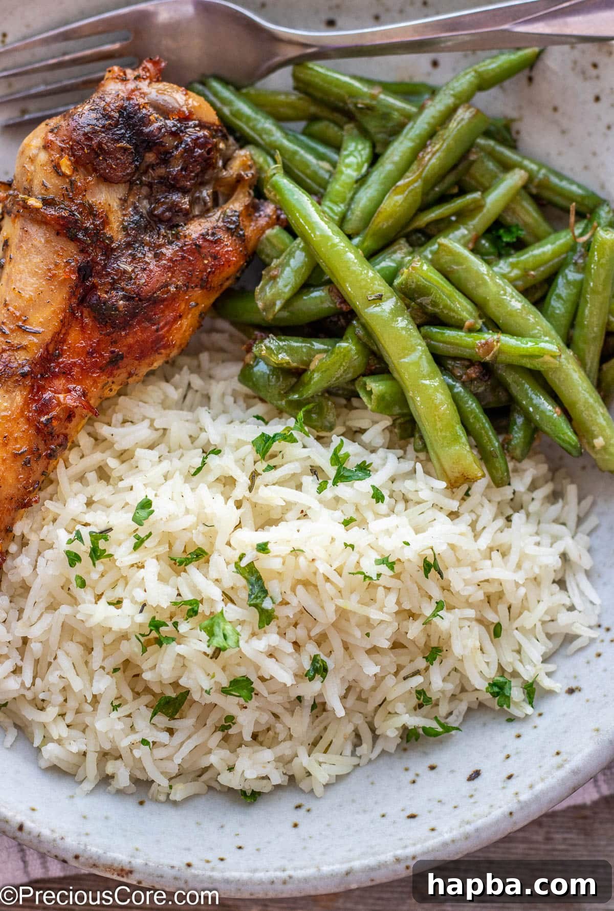 A single perfectly cooked turkey wing served on a plate with a generous portion of garlic herb rice and crisp green beans.