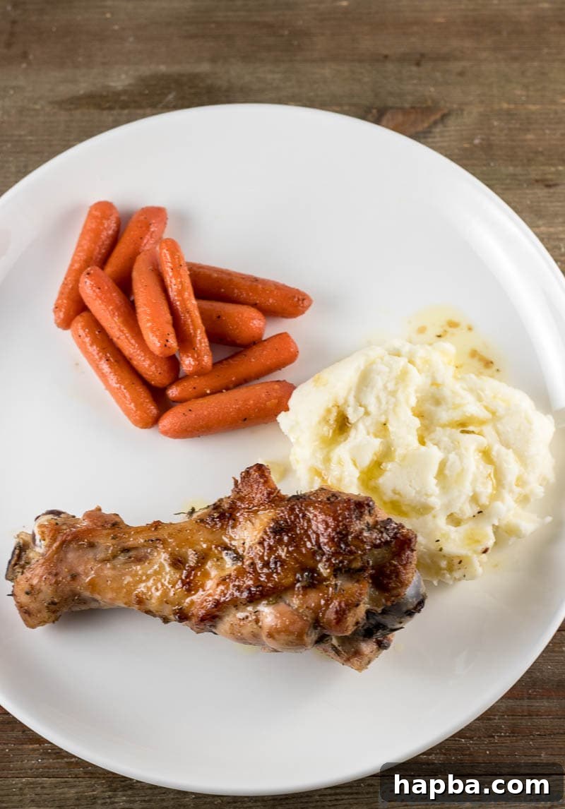 A plate featuring perfectly baked turkey wings served alongside creamy mashed potatoes and vibrant sautéed carrots, indicating a complete and satisfying meal.
