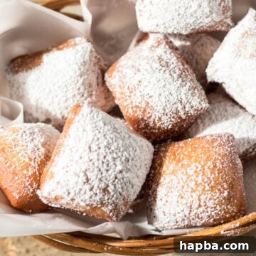 Basket of freshly made beignets, dusted with powdered sugar.