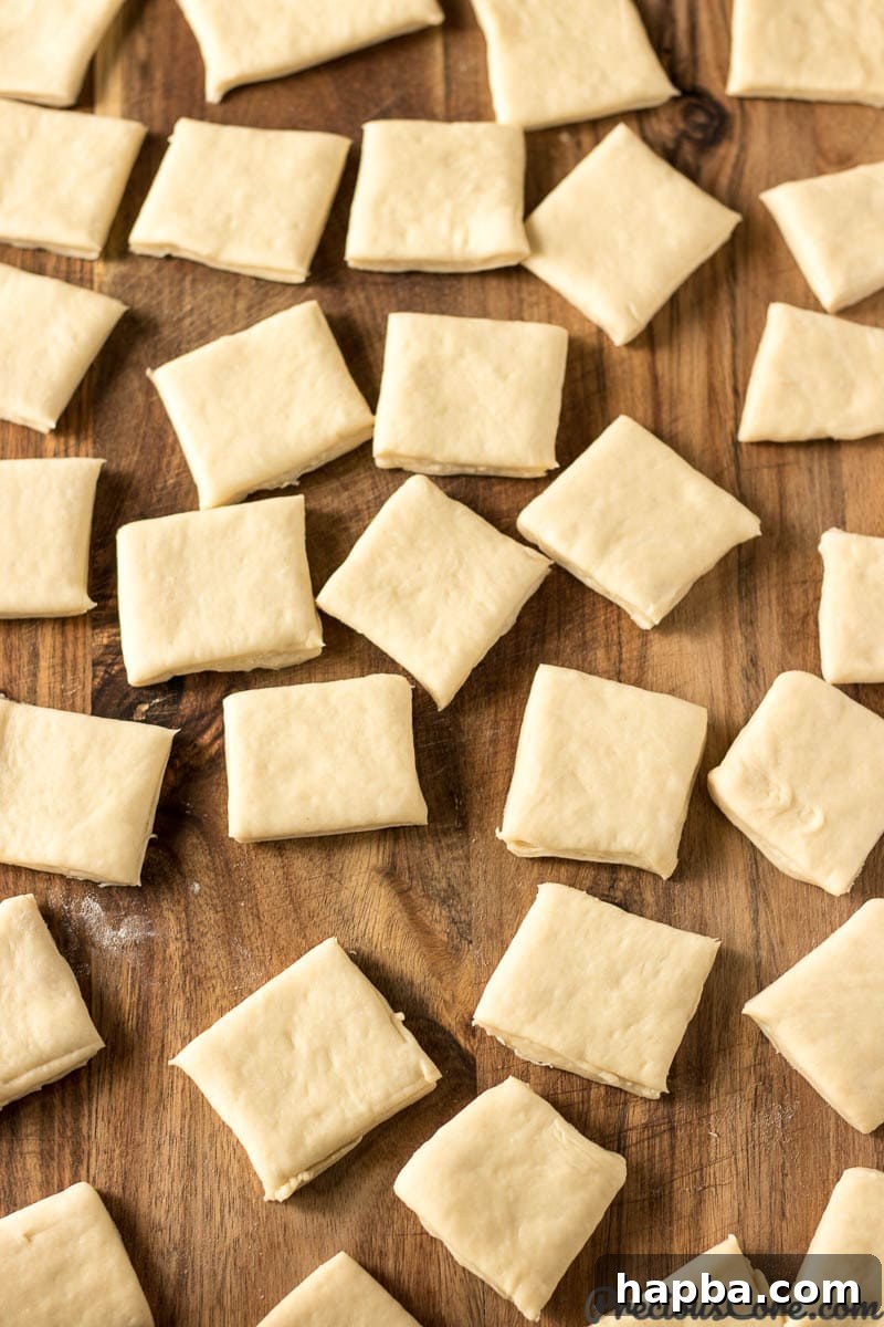 Big Easy Beignets 6 Close-up of beignet dough squares arranged on a wooden cutting board.