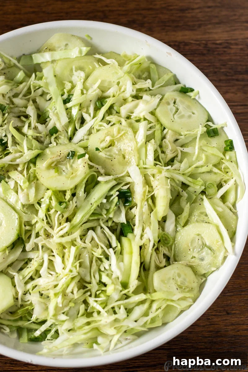 Refreshing Cabbage Slaw 7 The simple, tangy dressing being drizzled over the freshly prepared cabbage salad ingredients.