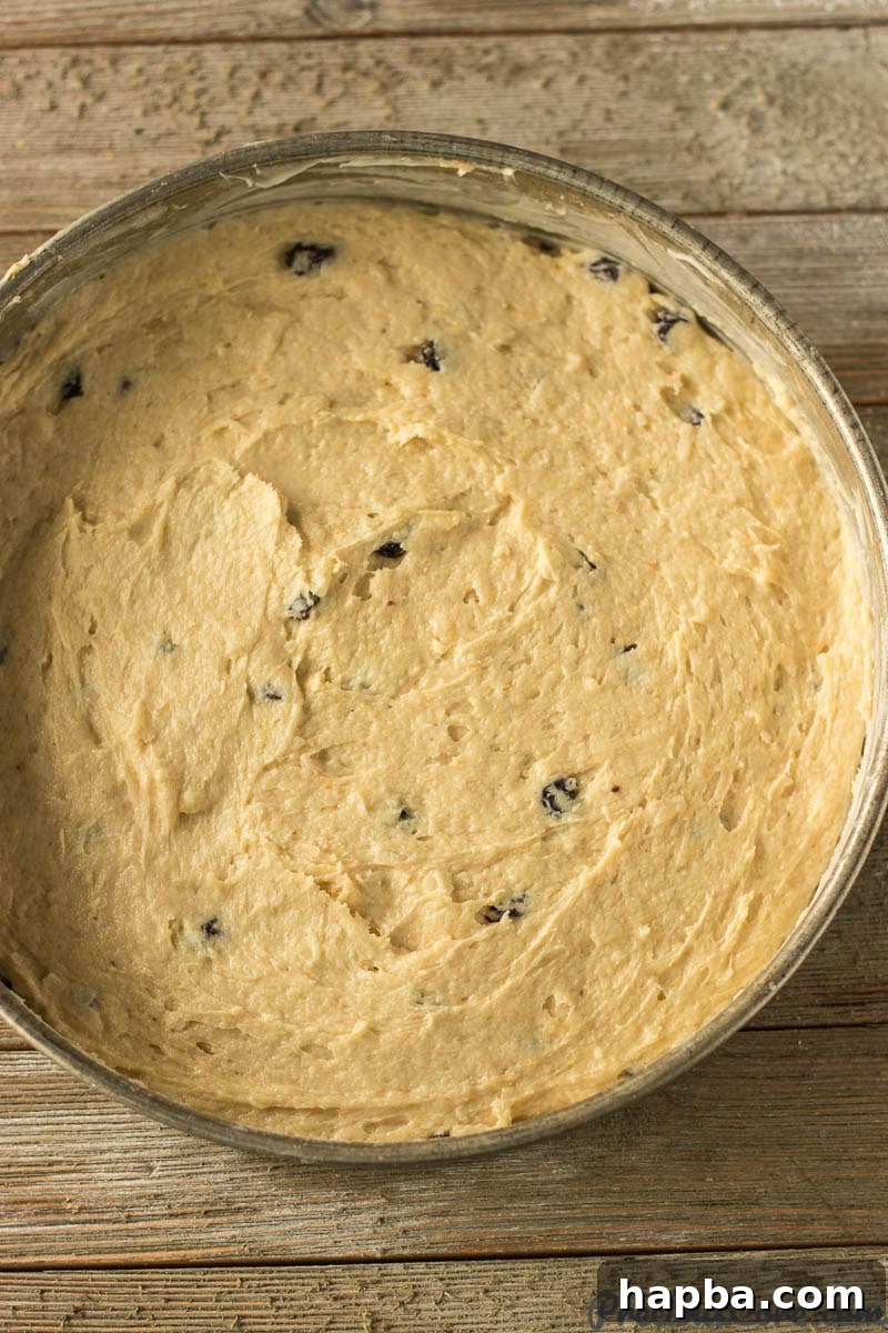 Christmas Fruit Cake batter evenly spread in a round cake pan, ready for baking.