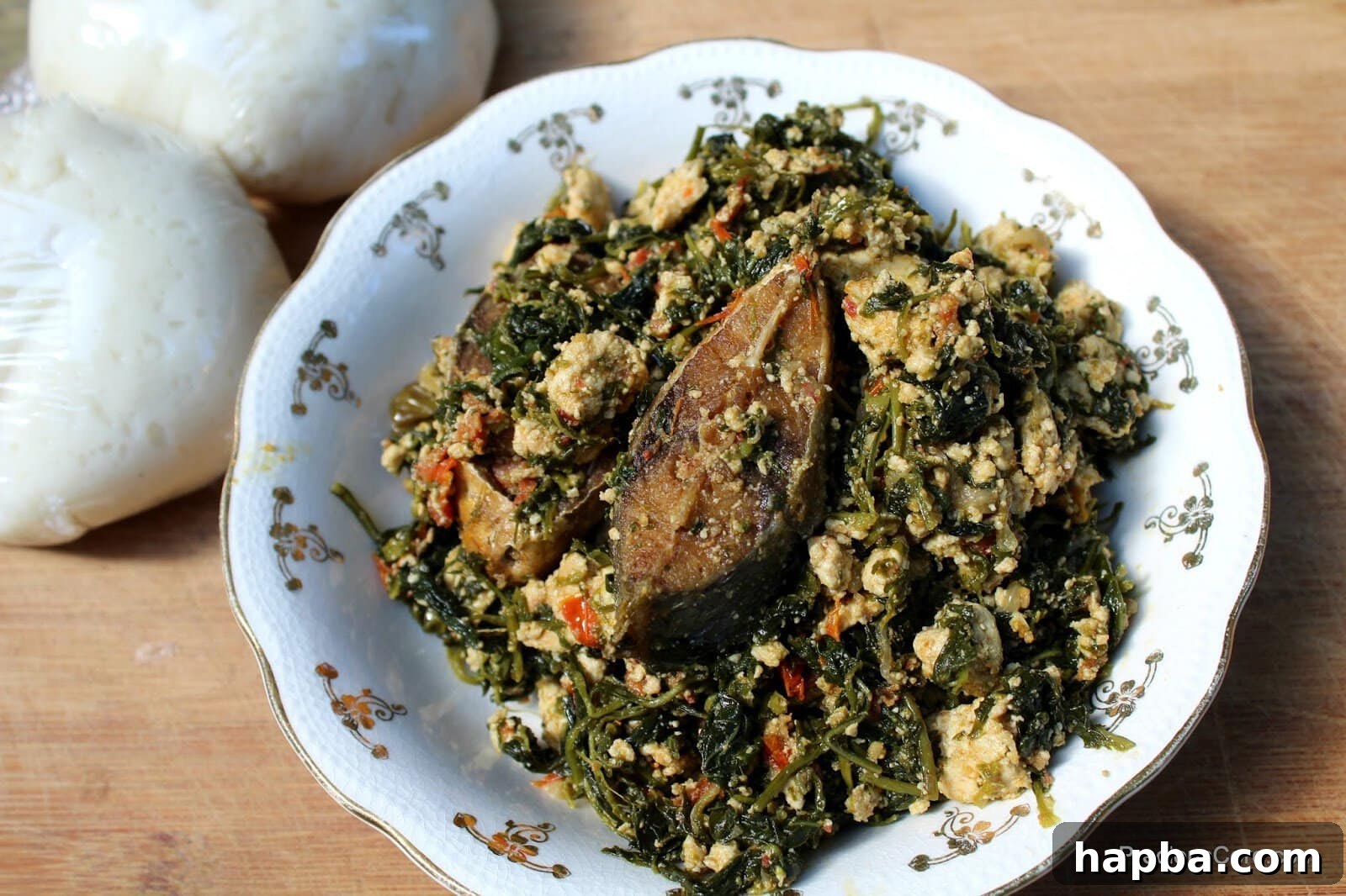 A bowl of Njama Njama with Egusi topped with fried fish, ready to be served.