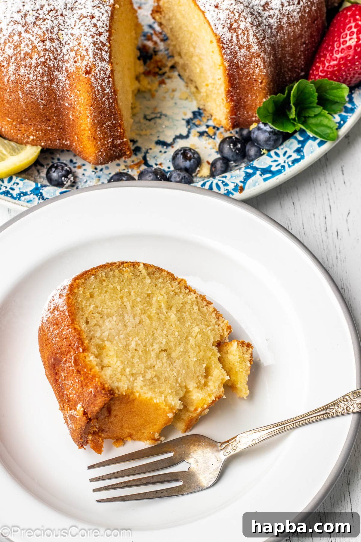 A perfect slice of golden lemon pound cake presented on a clean white plate, ready to be enjoyed.