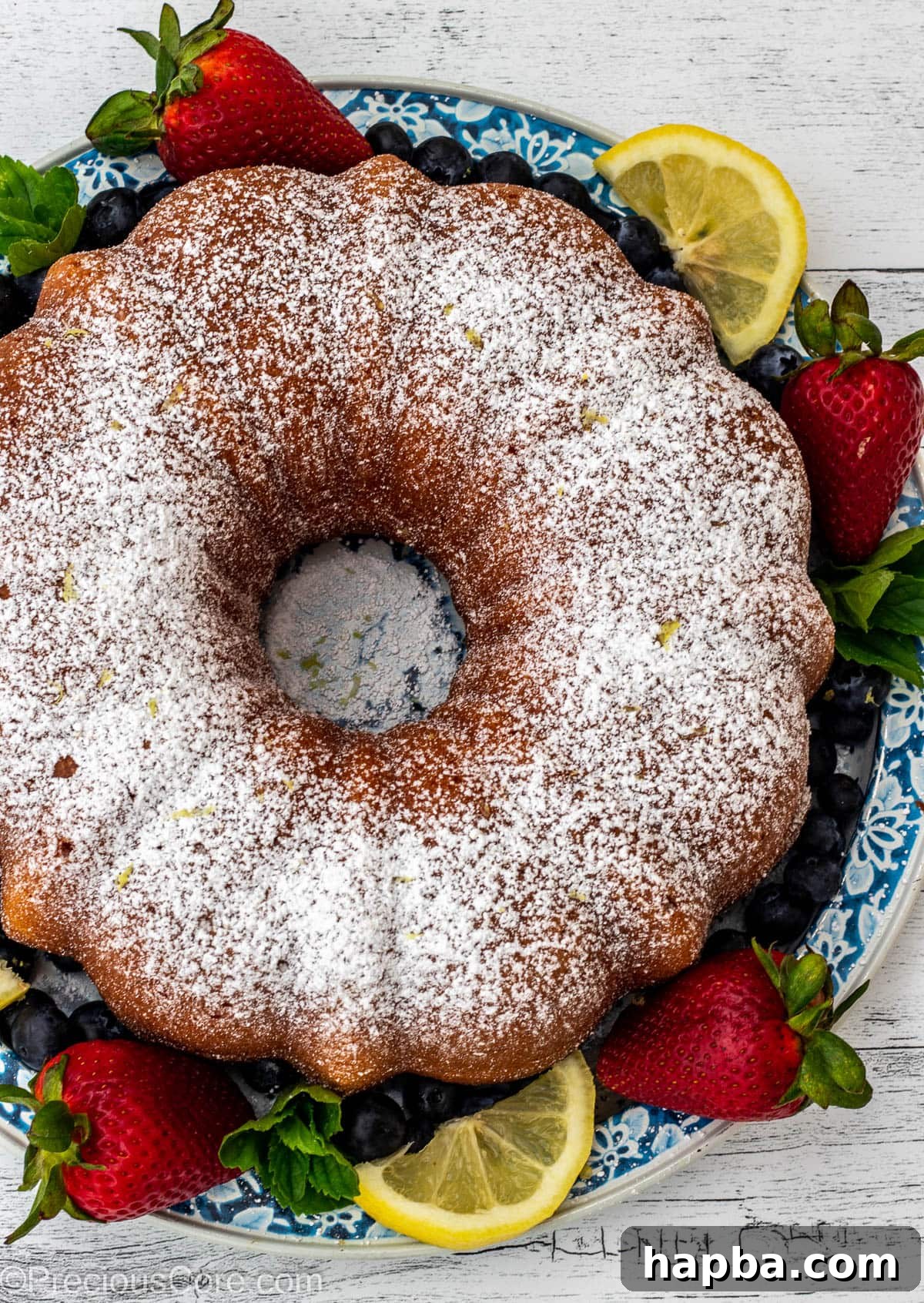 A beautifully baked bundt cake, lightly dusted with powdered sugar and adorned with a scattering of fresh berries.