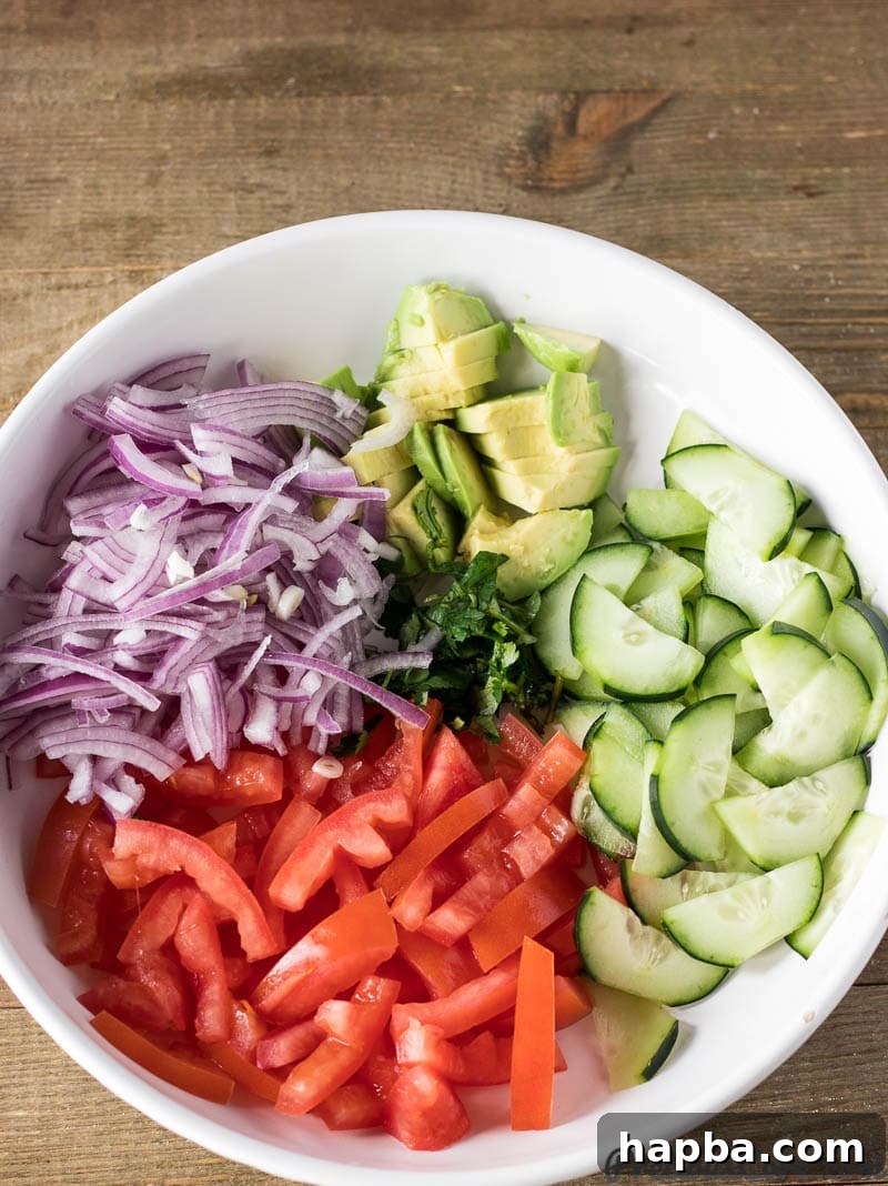 Kachumbari ingredients on a plate, featuring fresh tomatoes, red onions, cucumber, and avocado slices.