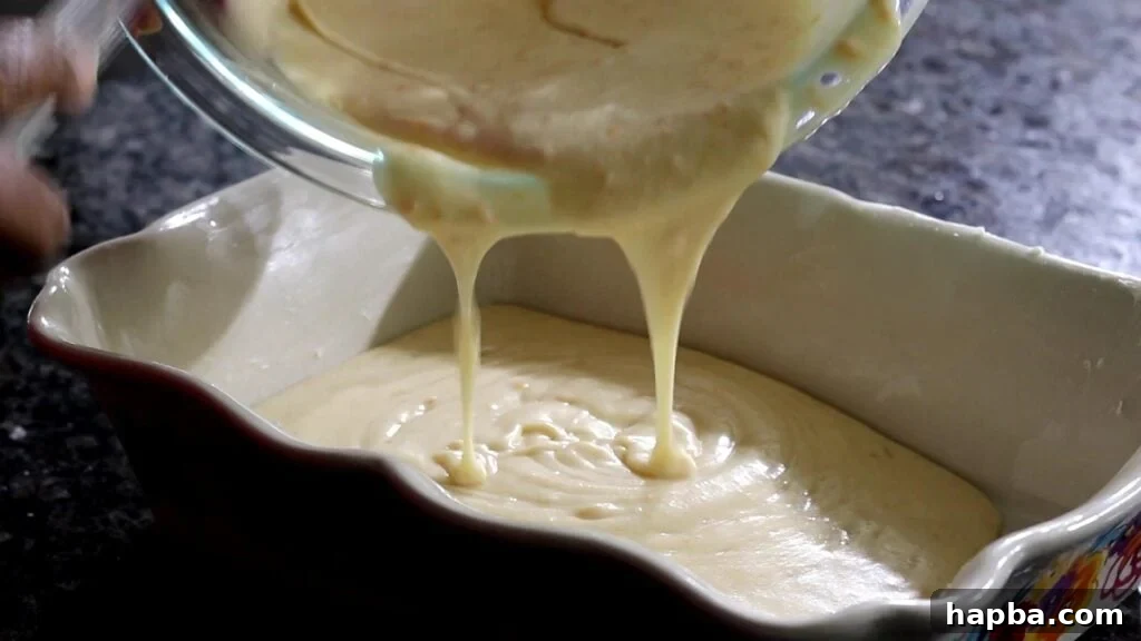 The smooth, light batter for South African Malva Pudding being poured into a greased baking dish, ready for the oven.