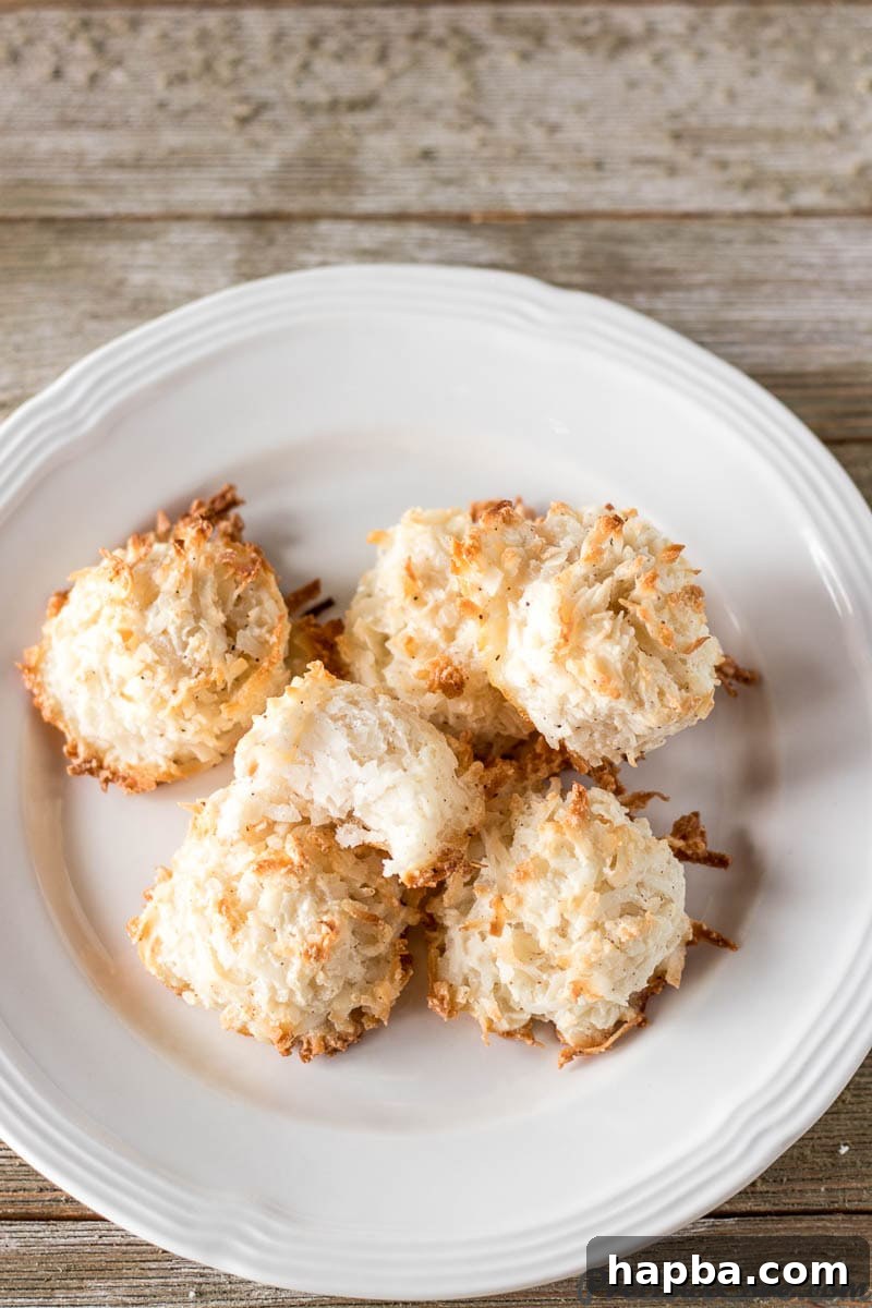 Effortless Coconut Macaroons 2 Golden-brown, perfectly baked coconut macaroons arranged elegantly on a small white plate, ready to be enjoyed.