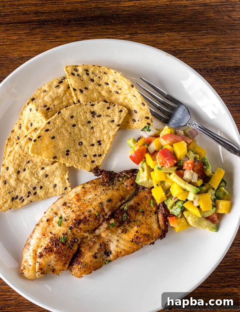 Mango Avocado Salsa served on a plate with grilled fish and tortilla chips.