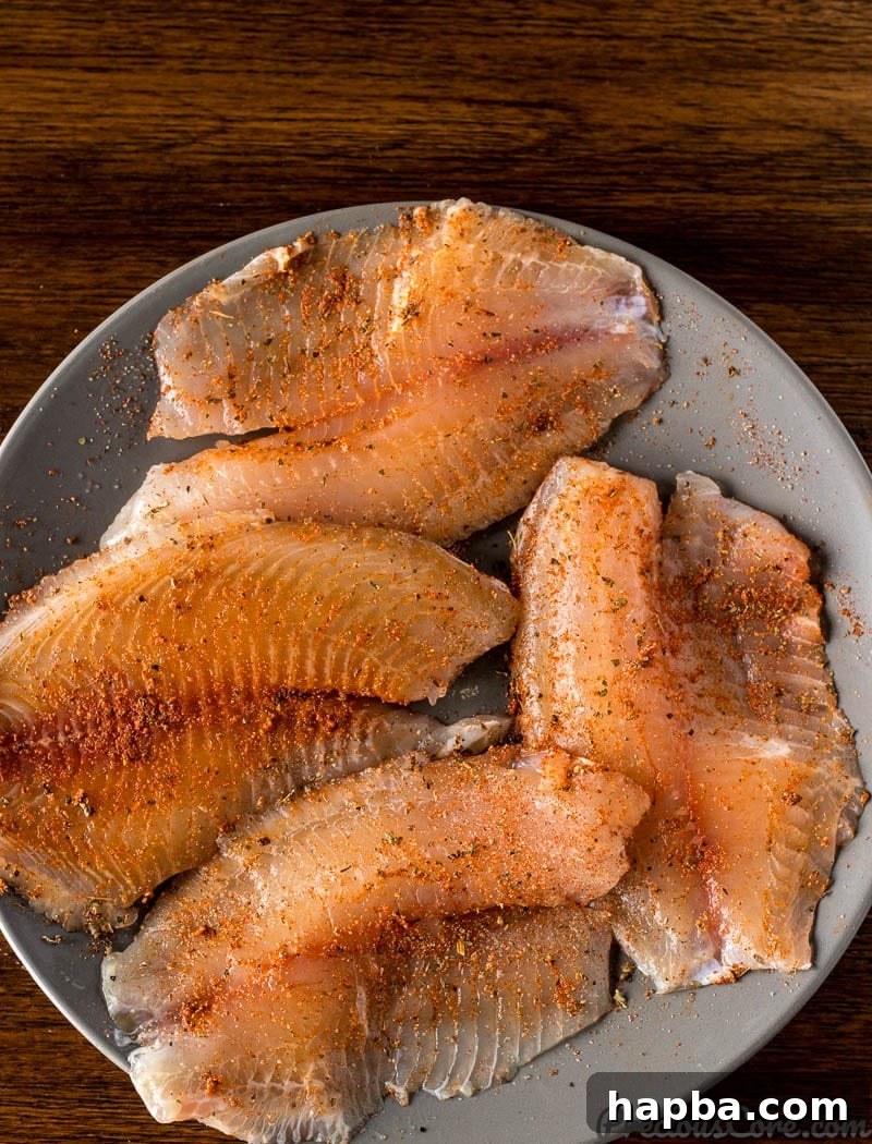 Golden Seared Tilapia 5 Tilapia fillets expertly coated with a blend of vibrant spices, ready for searing in the pan.