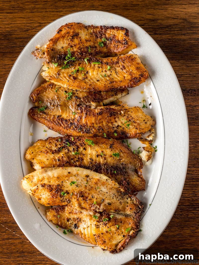 Golden Seared Tilapia 6 Freshly pan-seared tilapia fillets arranged on a tray, showcasing their perfect golden crust and readiness for serving.
