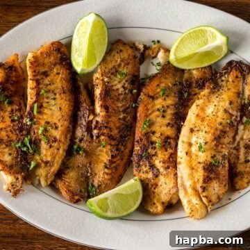 Beautifully Pan Seared Tilapia on a serving tray with fresh lime wedges, highlighting the golden crust.