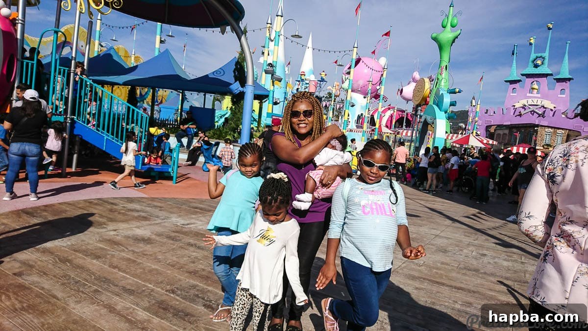 A joyful mother with her daughters exploring Super Silly Fun Land at Universal Studios Hollywood, surrounded by vibrant attractions.
