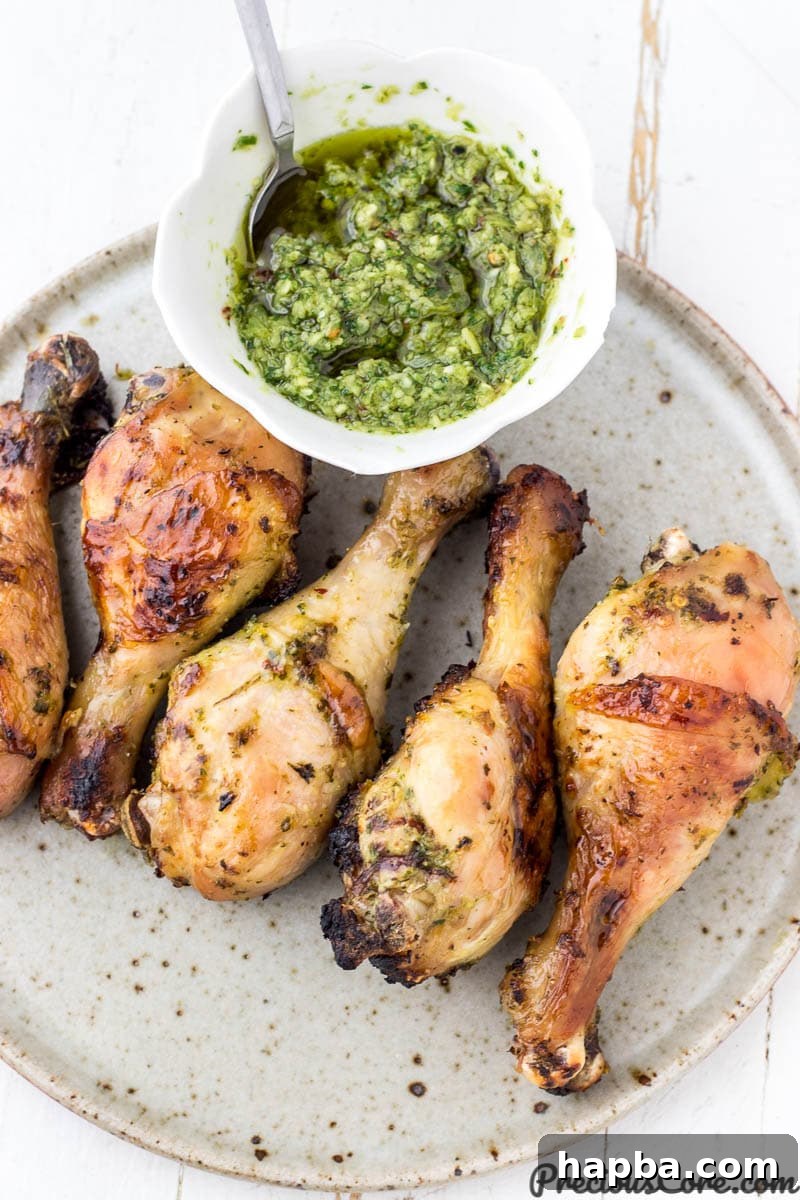 Vibrant Homemade Green Seasoning 3 Grilled chicken served on a plate with a side bowl of green seasoning, showcasing its use as a marinade and condiment.