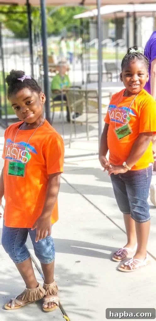 Two girls smiling in orange t-shirts.