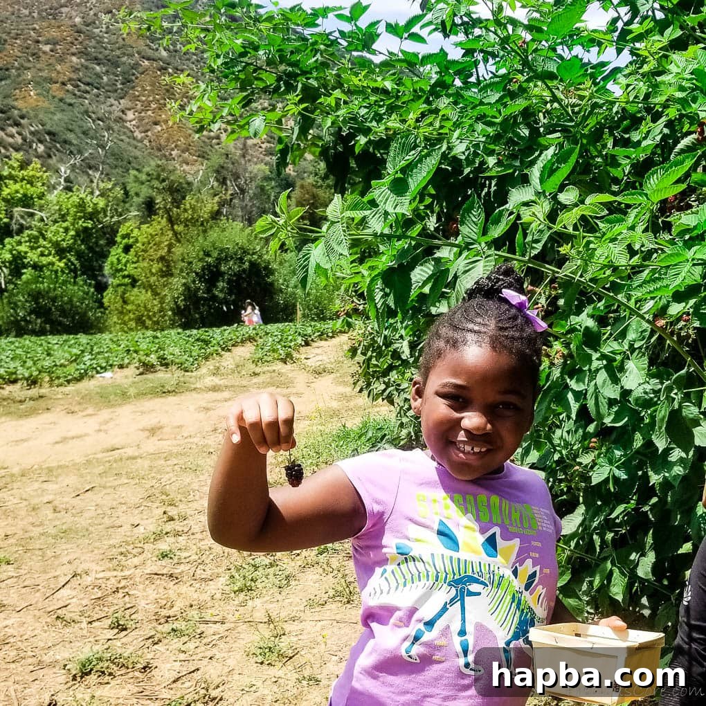 Girl smiling while holding a berry.