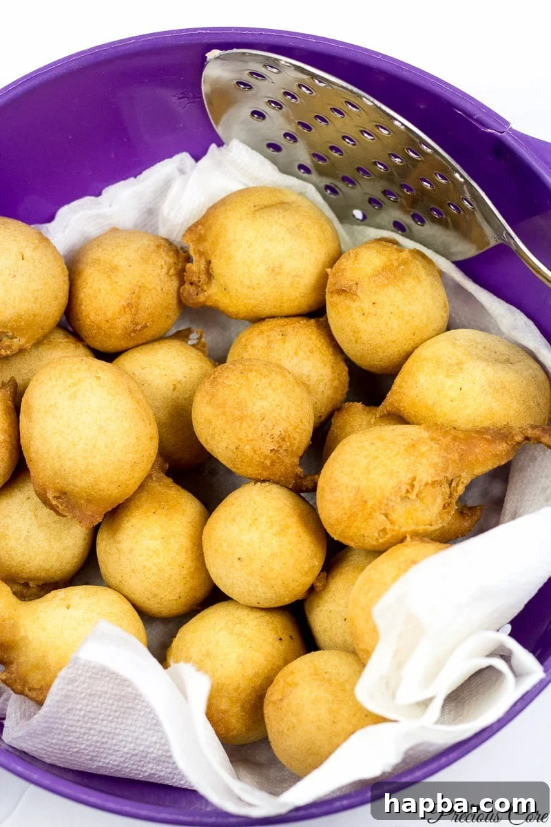 Cameroonian doughnuts cooling on paper towels in a bowl after frying.