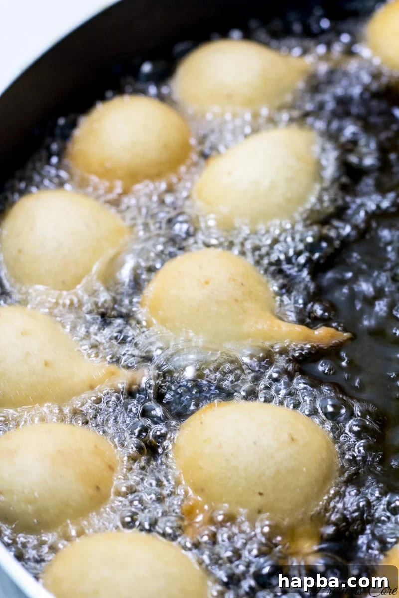 Cameroon doughnuts frying in hot oil, turning golden brown.