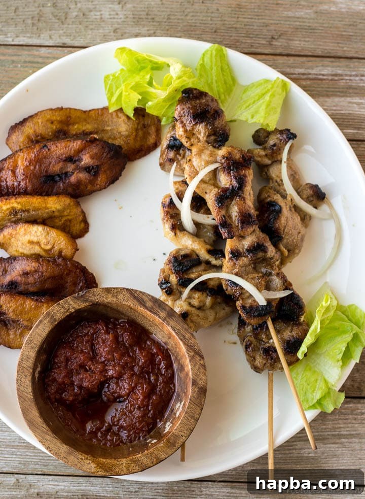 Grilled Chicken Skewers 7 Plated chicken skewers alongside a serving of delicious fried plantains