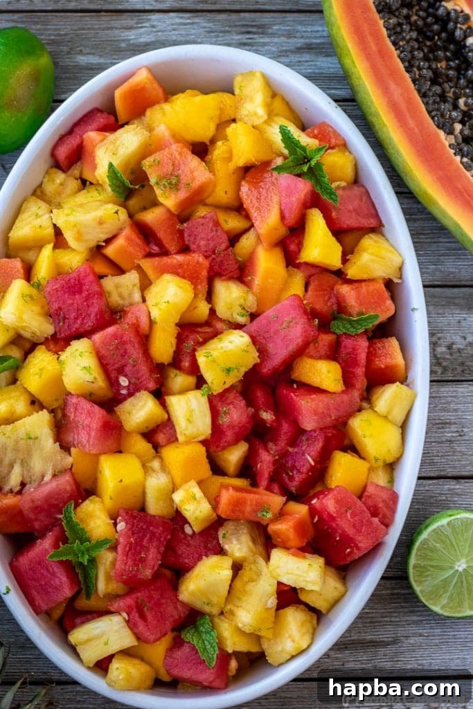 A bowl of fresh fruit salad, with half a papaya and a whole lime beside it, highlighting fresh ingredients.